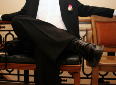  Best man in black suit sitting with legs crossed in a chair (hands out).