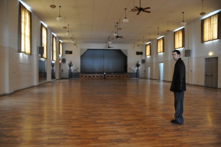 Groom standing alone in wedding ballroom.