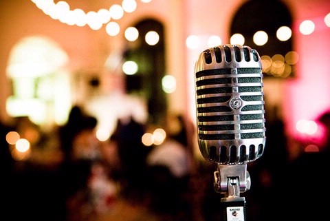 Old fashioned microphone with wedding reception in the background.