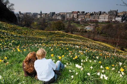 Man and women sitting in grass looking at city.