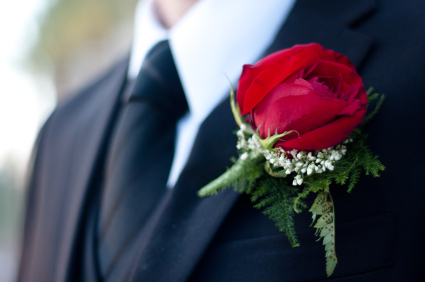 Groom in black suit with red rose boutonniere on his wedding day.